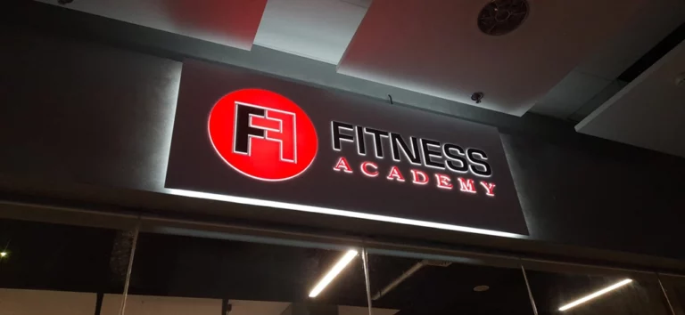 Czarny kaseton z wystającym napisem fitness academy i efektem halo