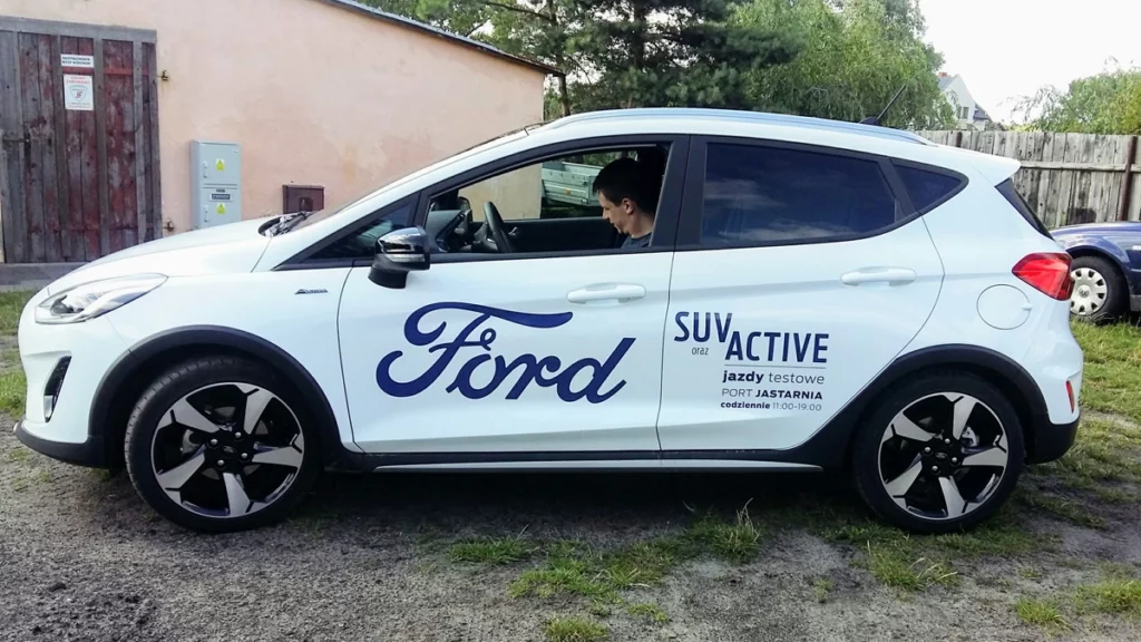 Biały Ford Kuga oklejony okazyjnie dla salonu wakacyjnego w porcie w Jastarni. oklejanie aut warszawa