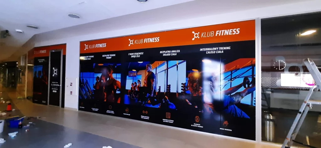 Witryny salonu Orange Theory Fitness z folią promocyjną. Oklejanie szyb Warszawa